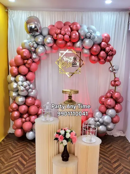 A stylish birthday setup with a rose gold and silver chrome balloon arch. This decoration uses a hexagonal "Happy Birthday" sign for a modern look.