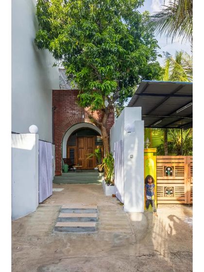 The 'House of No Windows' by ONEBULB ARCHITECTURE, shortlisted at WAF. The entrance is marked by a brick arch and a mature mango tree, demonstrating how the design preserves and integrates with the existing site.