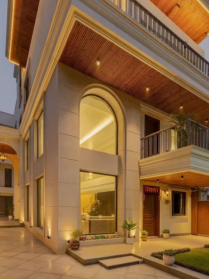 A closer view of the neoclassical house, focusing on the arched window and the interplay of stone cladding and smooth plaster. The design creates a sense of modern grandeur while respecting classical proportions.