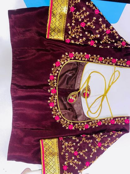 A simple but elegant design on a wine-colored velvet blouse. The pink floral embroidery on the neckline and sleeves stands out against the dark fabric.