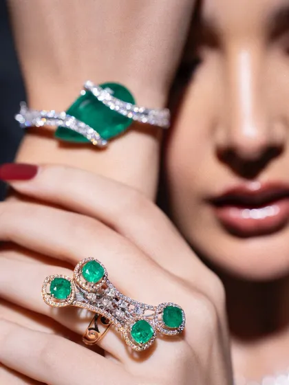 A detailed shot focusing on the wrist, showcasing a magnificent emerald bracelet and a multi-stone ring. This type of shot is crucial for highlighting the craftsmanship of specific pieces.