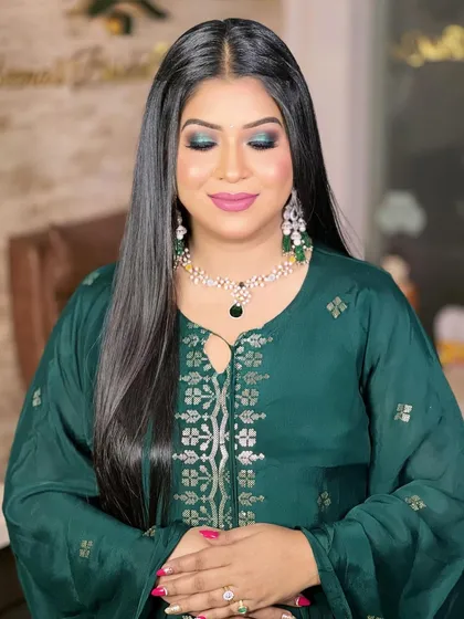 A glamorous look for a Mehendi night or cocktail party. The model wears a deep green outfit with dramatic smokey eye makeup and a sparkling diamond and emerald necklace.