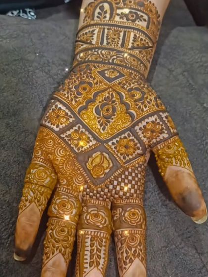 The full view of a best friend's mehendi, glowing with glitter. The checkerboard pattern covers the entire hand, creating a dazzling and celebratory effect.