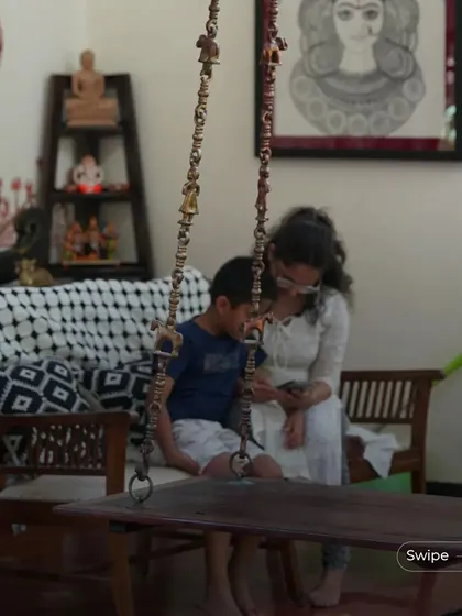 A mother and son share a moment on the indoor swing, which is a central feature of the living area. The swing adds a playful and traditional element to the home.