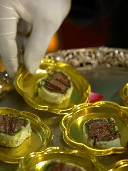 A chef carefully placing delicate, bite-sized sweets onto golden serving dishes. Every dessert is handled with care to ensure perfect presentation.