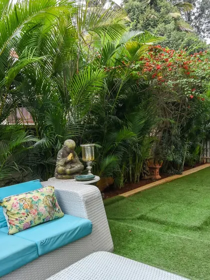 I believe a garden should be an extension of your living space. Here, comfortable outdoor furniture is nestled among tropical plants and a calming Buddha figure, creating a cozy and inviting nook for quiet reflection or conversation.
