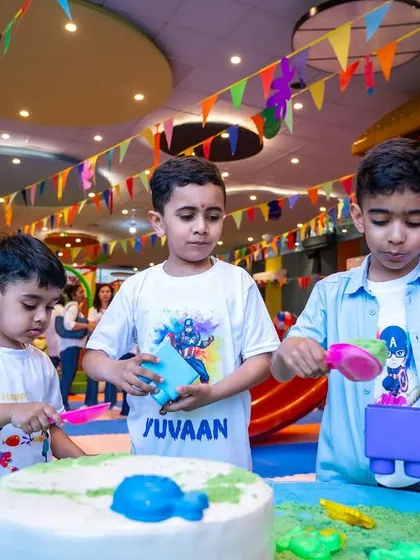 Three boys focused on a sand play activity during our Holi celebration. Even during festive events, our core play stations are always open for creative fun.