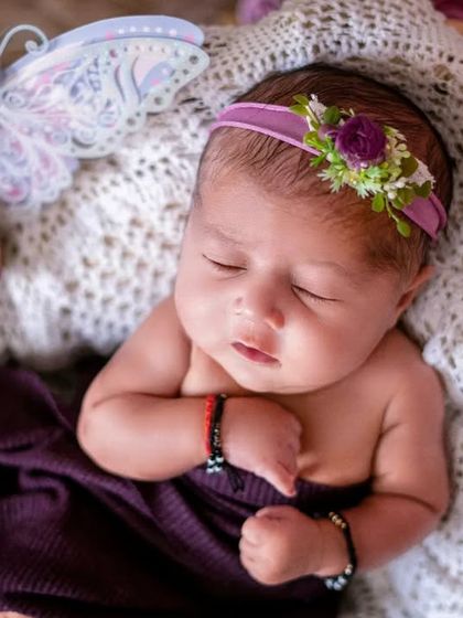 A sleeping butterfly. This newborn girl looks so peaceful and angelic, surrounded by purple flowers and a delicate butterfly prop.