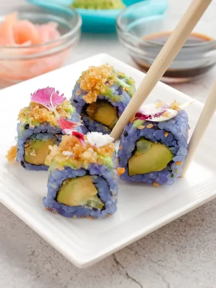 Our culinary creativity knows no bounds. These vibrant blue rice sushi rolls, filled with fresh avocado and topped with a delightful crunch, showcase our commitment to innovative, visually stunning, and purely vegetarian gourmet food.