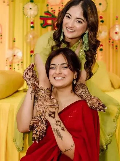 A lovely moment between two sisters at a mehendi ceremony, both adorned with my designs.