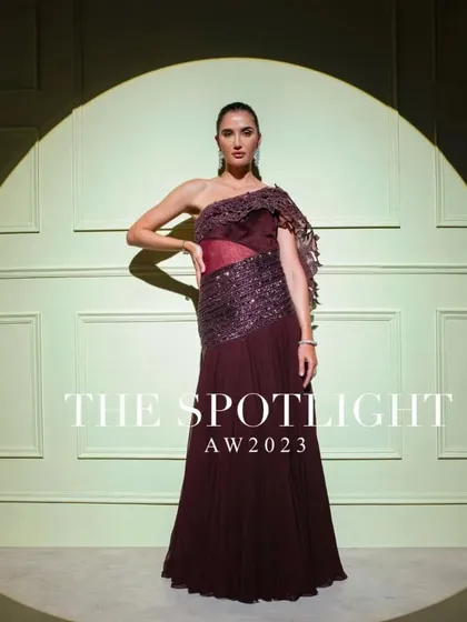 A full campaign shot of the one-shoulder wine-colored gown, a perfect example of modern, structured elegance.