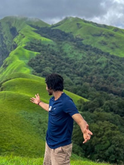 A trekker embracing the vast, open landscape of Netravati peak. The feeling of freedom here is unparalleled.