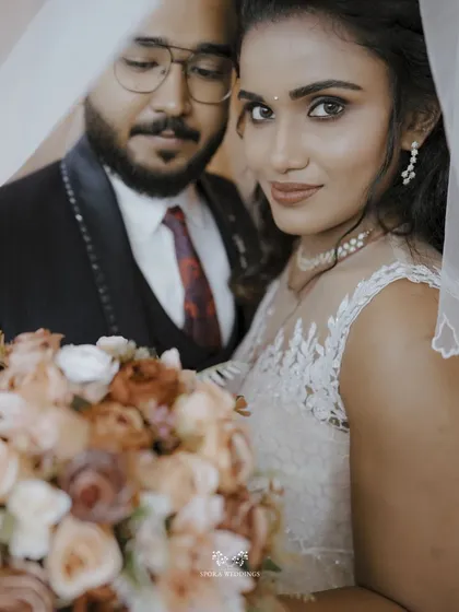 An intimate portrait of the couple, the bride looking directly at the camera from under her veil, creating a captivating and romantic image.