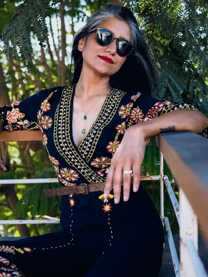 This shot highlights the intricate embroidery on the jumpsuit.