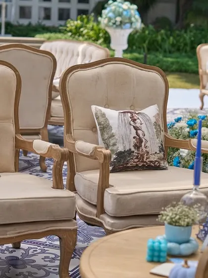 Elegant, French-style armchairs with custom-printed cushions, arranged on the blue and white tiled floor.