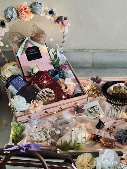 A glimpse into a dreamy bridal trousseau hamper. This arrangement features a collection of luxury cosmetics, fine perfumes, and elegant accessories, all beautifully presented in a floral-themed basket with delicate lighting.