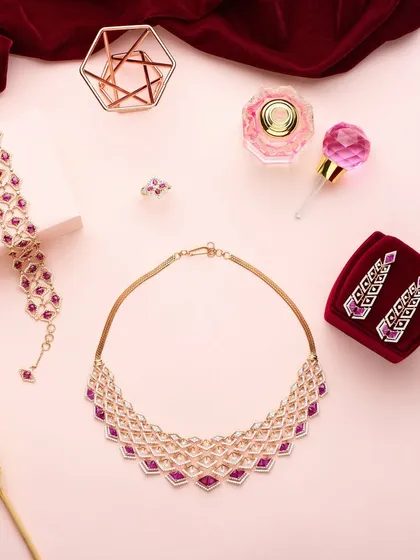 A rich, luxurious flat lay for PNGadgil and Sons. The deep red velvet and soft pink background create a romantic mood, perfectly complementing the ruby and diamond jewelry set.