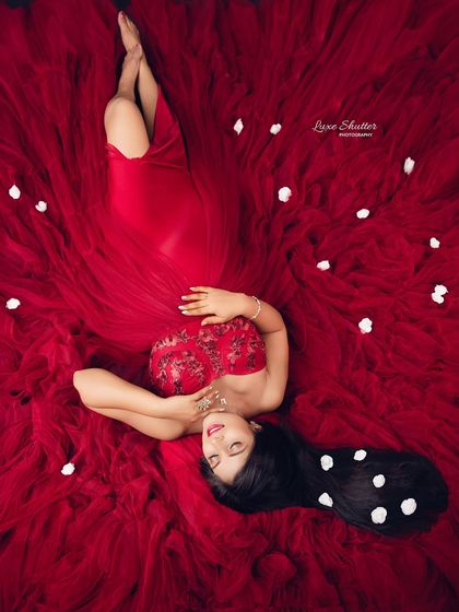 A truly artistic and unique perspective. This top-down shot transforms the flowing red gown into a beautiful canvas, with the mother-to-be as the serene centerpiece.