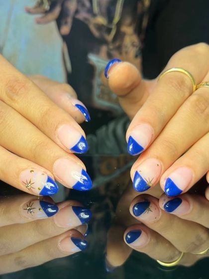 A modern geometric take on the French manicure, featuring bold royal blue polish applied in a sharp, angular design on a sheer base.