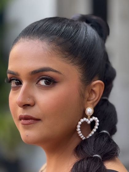 For this look, we focused on clean lines and statement accessories. The bubble ponytail and heart-shaped pearl earrings add a touch of personality to the classic black and white dress.