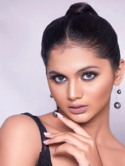 A high-fashion pose showing off the clean lines of the makeup and hairstyle.