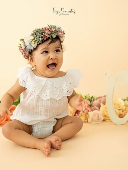 A happy, open-mouthed giggle from this little flower child. Her joy is contagious in this beautiful floral-themed first-year portrait.