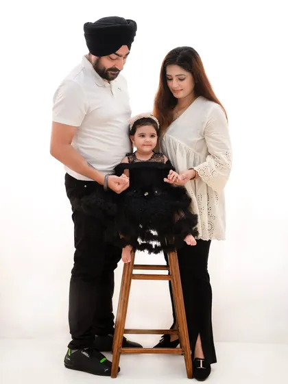 A classic standing portrait of a family of three. The minimalist setting ensures that the family's connection and their coordinated, elegant outfits are the main subject.