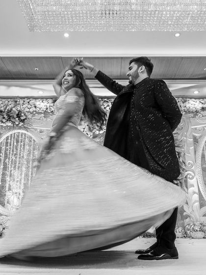 A beautiful black and white shot of the groom twirling his bride on the dance floor, capturing the motion and joy of the moment.