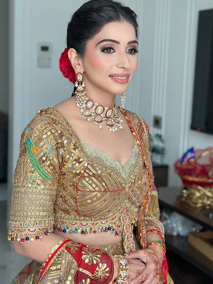 A bride ready for her wedding day in a stunning Rimple and Harpreet ensemble. Her hair is in a braided updo with a single red rose, adding a touch of romance.