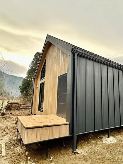 A modern barn-style prefabricated home under construction in a mountain setting. This design combines traditional aesthetics with the speed and efficiency of modular building techniques.
