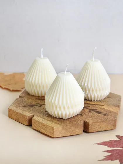 A trio of our pear-shaped candles on a wooden coaster. These are perfect for adding a festive and elegant touch to your decor.