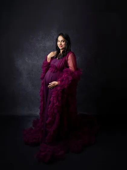 This shot highlights the elegant silhouette of the mother-to-be in her flowing purple gown. It's a beautiful way to showcase the baby bump in a stylish and artistic manner.