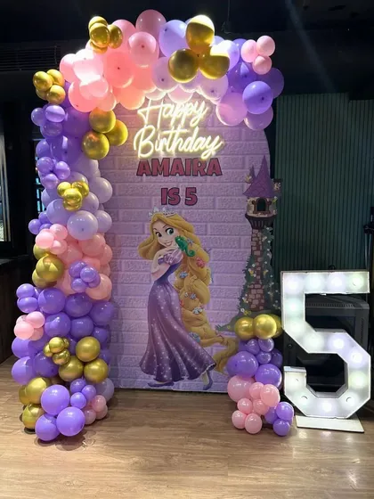 Let your hair down! This Rapunzel-themed decoration for Amaira's 5th birthday featured a tower backdrop and a beautiful balloon arch in shades of purple, pink, and gold. The large, illuminated '5' made the princess's day shine even brighter.