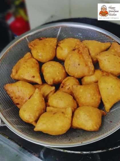 Freshly fried samosas being lifted from the pan. This is the moment just before they are ready to be served, capturing the delicious texture and colour of our handmade treats.