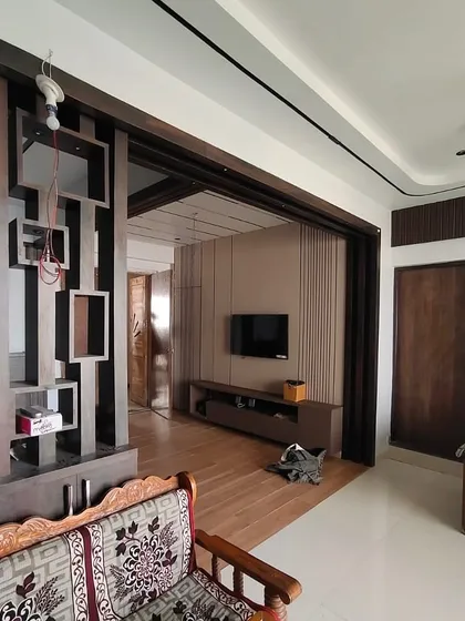 A wider angle of the living room during construction, showing the overall layout and the scale of the custom furniture being built on-site.