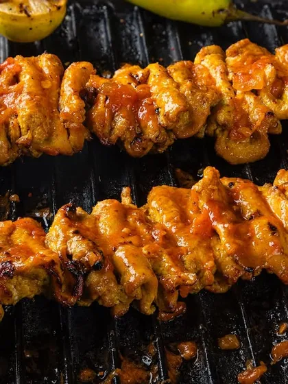Chicken tikka skewers on a grill, showing the moment of cooking. This dynamic shot for Punjab Grill is designed to evoke the sounds and smells of a barbecue.