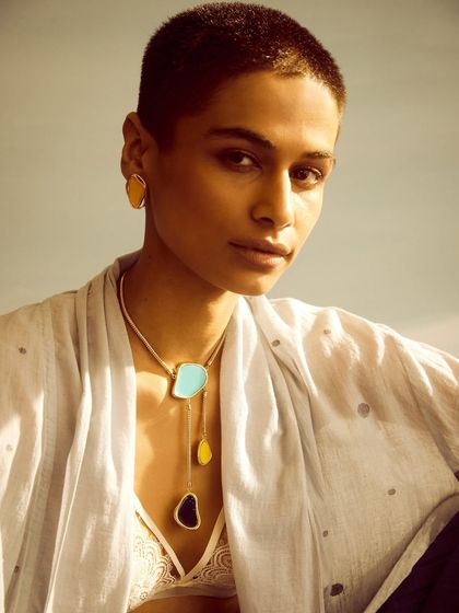 A layered necklace look against a simple white top. This demonstrates how the jewelry can be styled in a more casual, contemporary way.