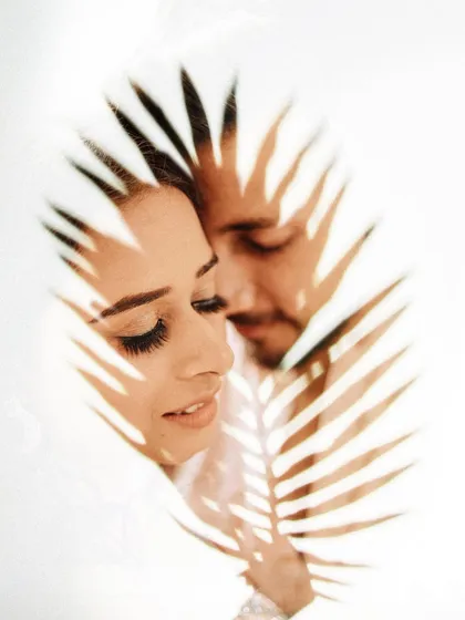 An artistic portrait using a palm leaf to create interesting shadows on the couple's faces. This creative technique adds a unique and intimate feel to their pre-wedding photo.