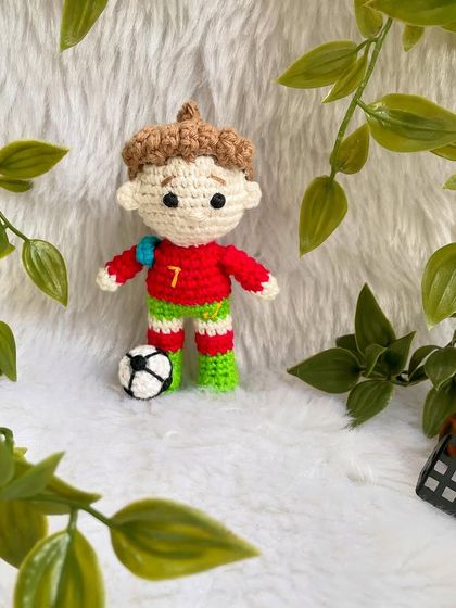 A mini replica doll of the football superstar Cristiano Ronaldo, CR7! This keychain-sized doll is ready for the field with his jersey and a tiny football.