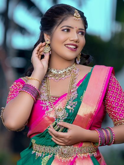 A happy bride wearing a Victorian-style set with green stones. The layered necklace adds a lot of charm to her look.