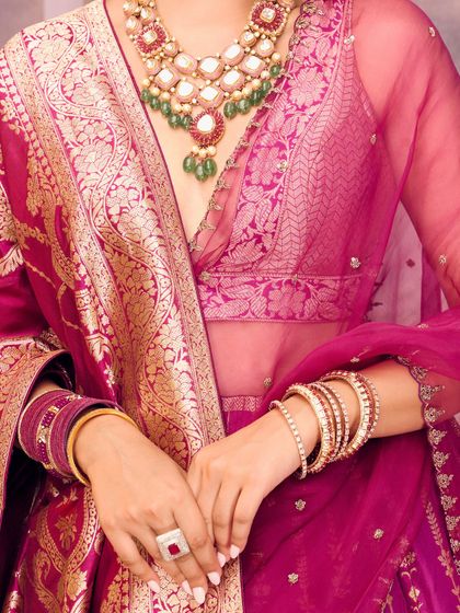 A close-up of the rich brocade fabric and the layered jewelry, showing how to style a traditional outfit with a touch of modern glam.