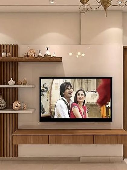 We designed this compact and efficient TV unit for a smaller living space. It features a simple floating console and asymmetrical floating shelves next to a fluted wood panel, providing storage and style without overwhelming the room.