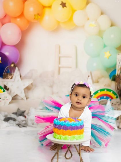 A sweet portrait before the cake comes out. The rainbow theme provides a bright and cheerful backdrop for any first birthday photoshoot.
