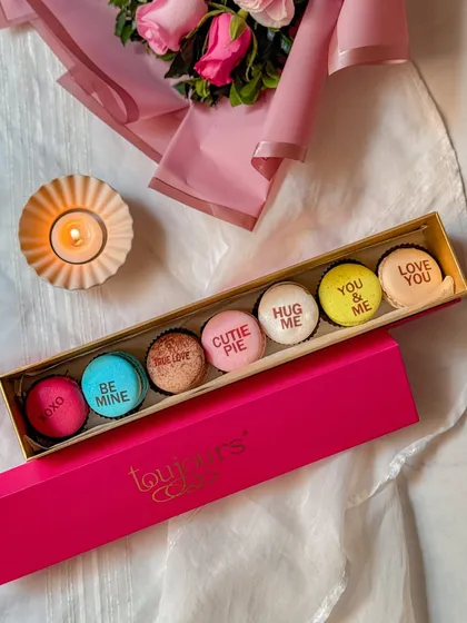 A bright pink box of my Valentine's Day message macarons, with sweet phrases like "Be Mine," "Cutie Pie," and "You & Me." These are a playful and colorful way to express your feelings.