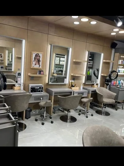 The styling stations inside the Enrich salon. This project involved using a sophisticated palette of wood panels, grey tones, and soft lighting to create a calm and professional environment for a premium salon experience.