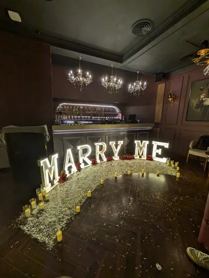 Another perspective of the 'MARRY ME' light-up letters, showing the careful placement of candles and petals to enhance the romantic ambiance of the proposal venue.