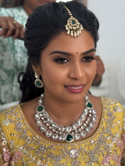 A smiling portrait of Abi, looking happy and confident in her reception makeover. The makeup is soft yet glamorous, perfect for her yellow lehenga.