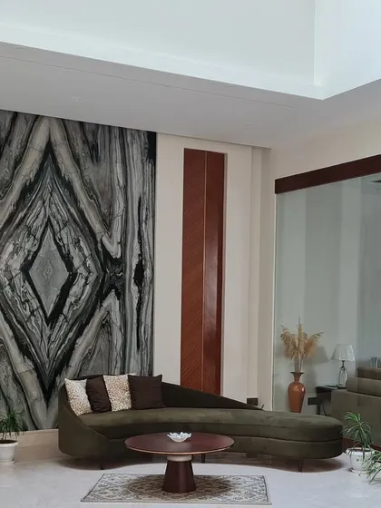 A dramatic book matched marble wall serves as the artistic focal point in this living area. Paired with a curved chaise lounge, the space is a dialogue between natural art and sculptural furniture.
