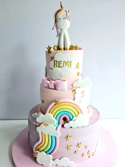 This three-tiered unicorn cake is all about pastel dreams. It features a rainbow cascading down the side, fluffy clouds, and a cute unicorn topper, making it a truly magical centerpiece for a fifth birthday.