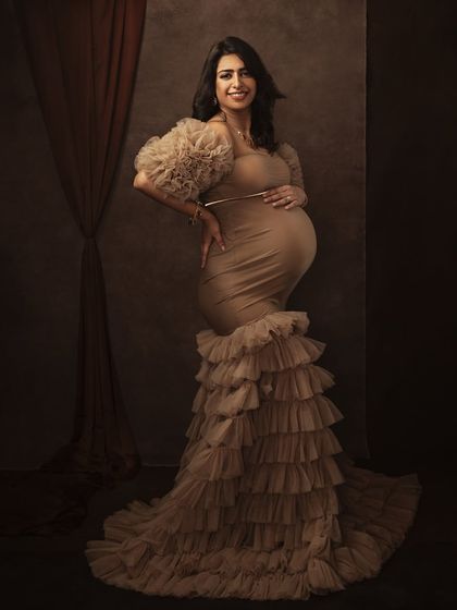 A full-body portrait that captures the grandeur of the gown and the confident posture of the expecting mother.